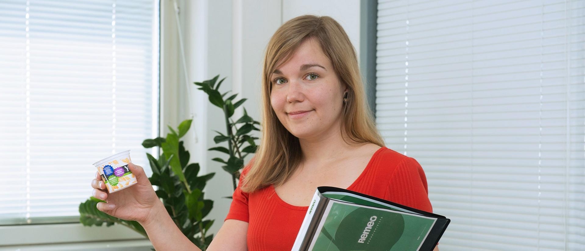 Nainen hymyilee joguttipurkki kädessään