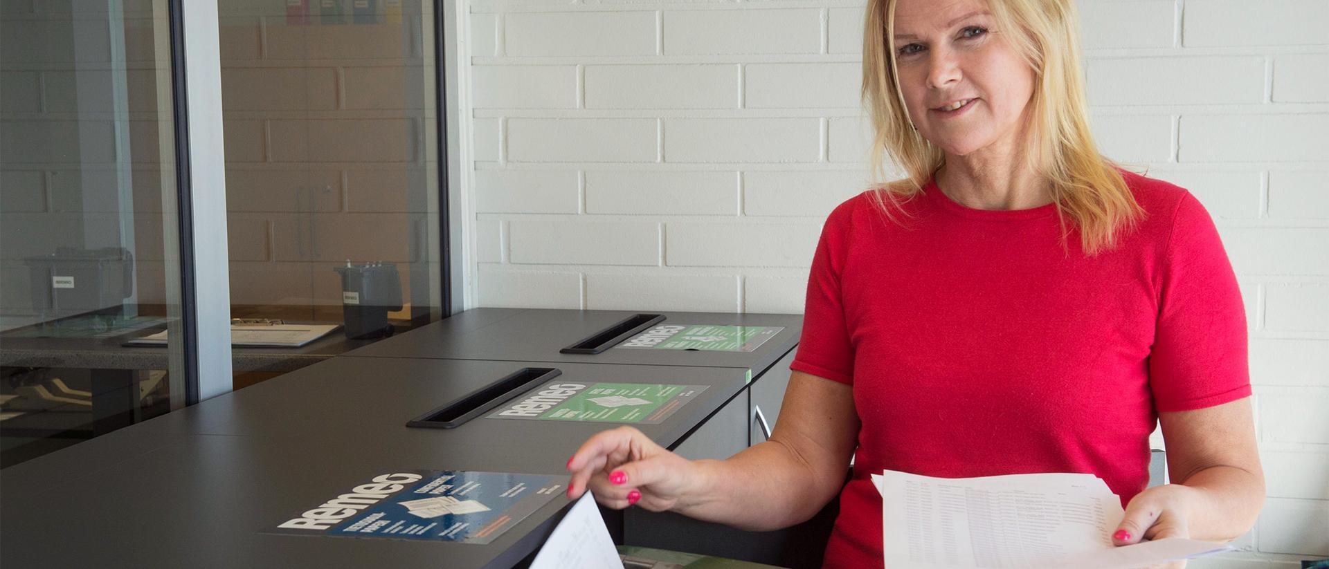 Nainen laittaa paperia tietoturva-astiaan
